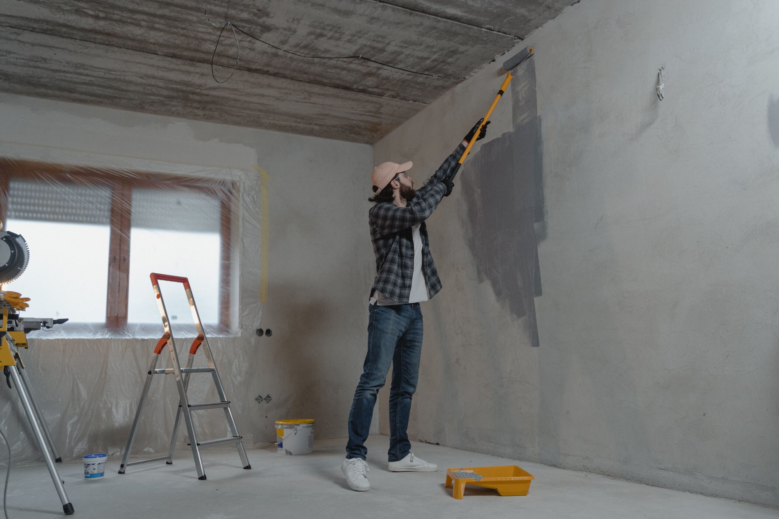 service-1 A man painting an interior wall with a roller during a home renovation project.